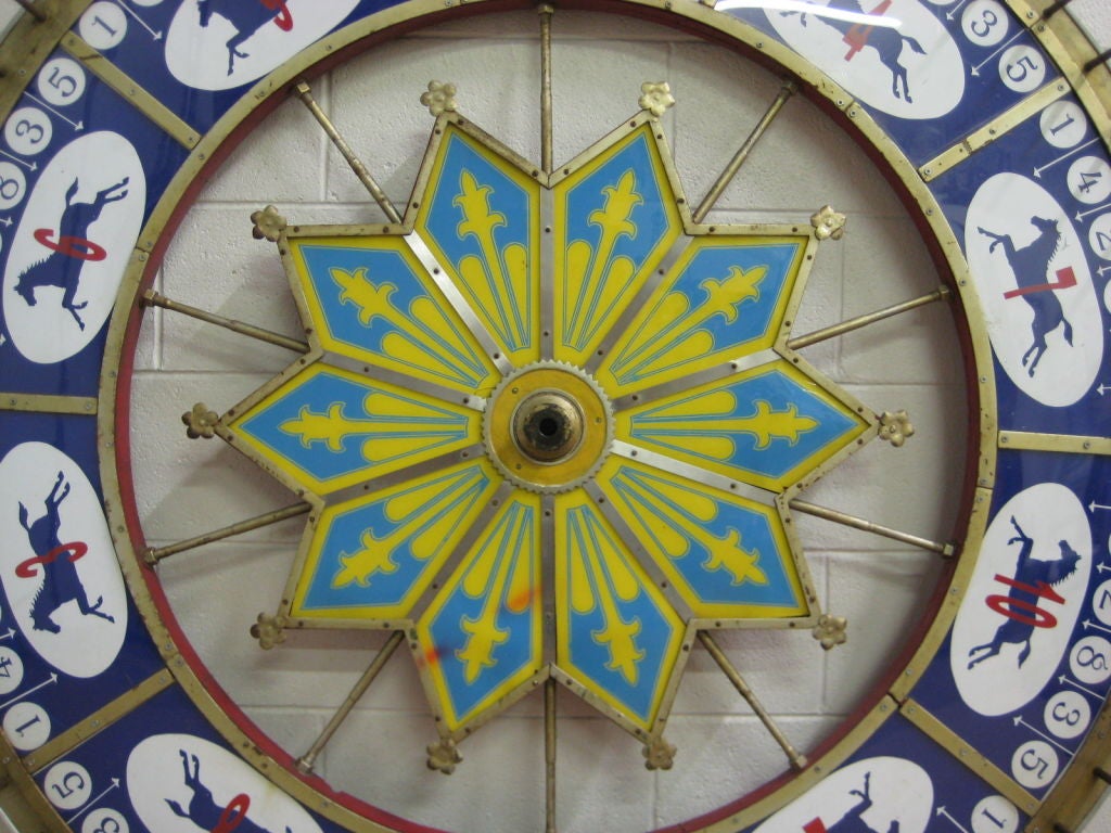 Vintage race horse gaming wheel made of wood and faced with plexiglass with metal trim and pins. Back is painted red and stamped 