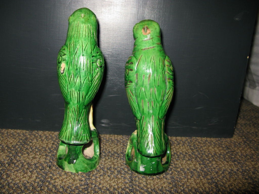 A pair of small 19th century Chinese green Parrots, sitting on stylized tree stumps.
