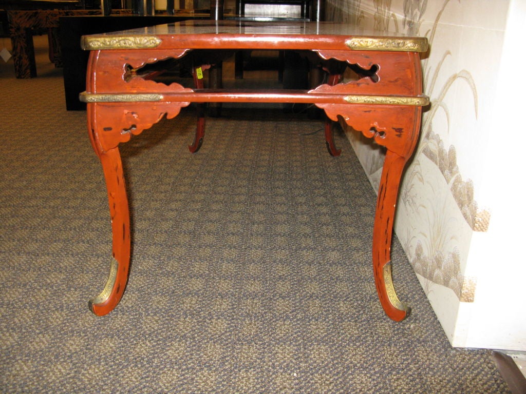 A stunning 19th century Japanese red lacquer table.<br />
-Graceful, curved legs<br />
-Open work in apron<br />
-Detailed decorative metal hardware at corners and bases of legs.<br />
-Red, with hints of black in a few areas.