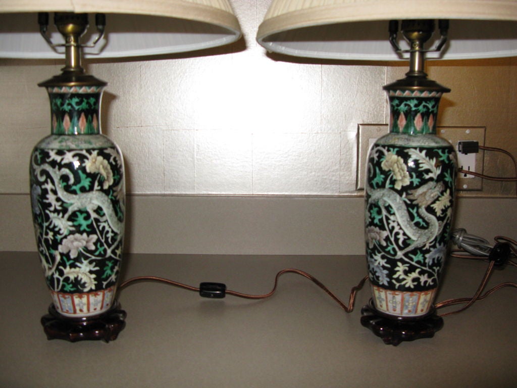 A beautiful small pair of Chinese famille noire vases with design of scrolling vines, flowers and dragons.<br />
<br />
Mounted as lamps.<br />
<br />
Shades included in price.