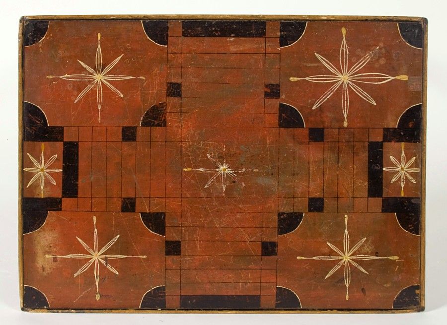 New Hampshire or Vermont game board table with a large-scale Parcheesi board. The salmon ground of the surface is adorned with the same black/midnight brown used on the tapered, lambs-tongued legs, skirt, and molded edge. The eight-pointed