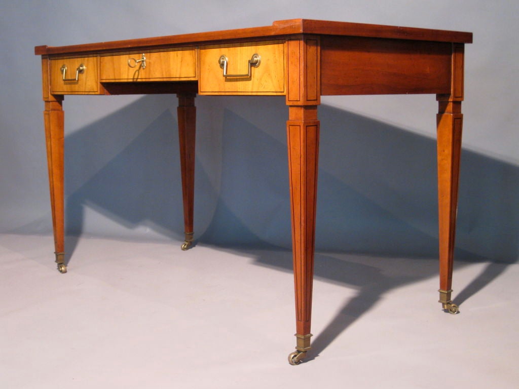 Neoclassical three drawer desk with diamond pattern inlaid writing surface and brass hardware made by Baker c.1960's. Inlaid tapered legs with brass sabots and casters. In the style of Jean Michel Frank or Maison Jansen. Beautiful original finish.