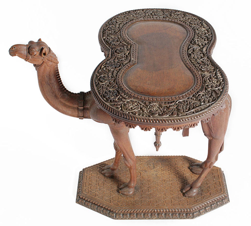 A Syrian carved sandalwood table modeled as standing camel with an hour-glass shaped table top.