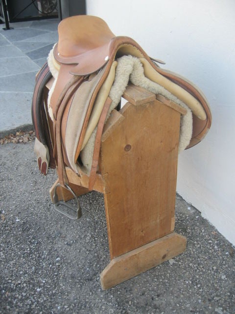 Used jumping saddle, saddle blanket, cinch belts, and wooden stand. Gently used and in excellent condition. The leather is dark tan. The saddle blanket is sheep skin.