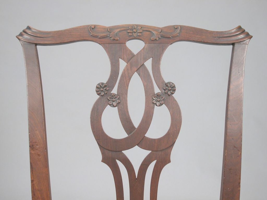 A pair of Chippendale Mahogany Side Chairs with Cupid`s bow shaped crests and pierced scrolled splats over a rectangular slip seat on cabriole legs ending in ball and claw front feet.  The crest carved with leaf and rosette motif the splat with