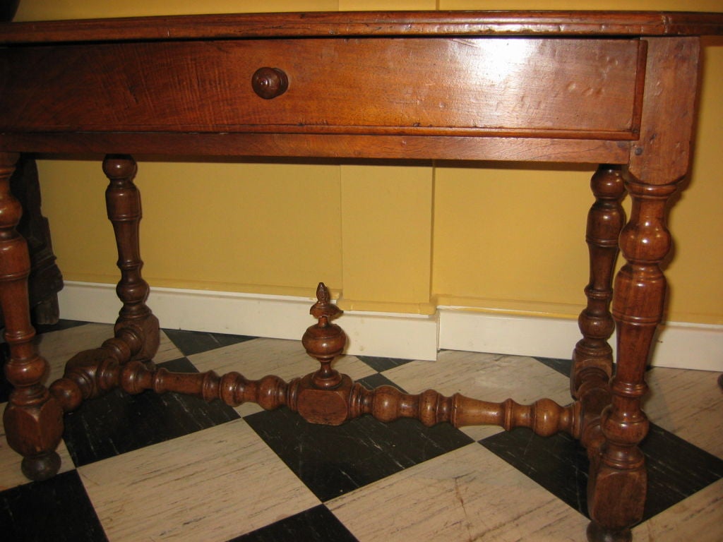 A French late 17th/early 18th century walnut table with centre drawer and turned legs with turned stretchers mounted by a turned finial. Circa 1720
