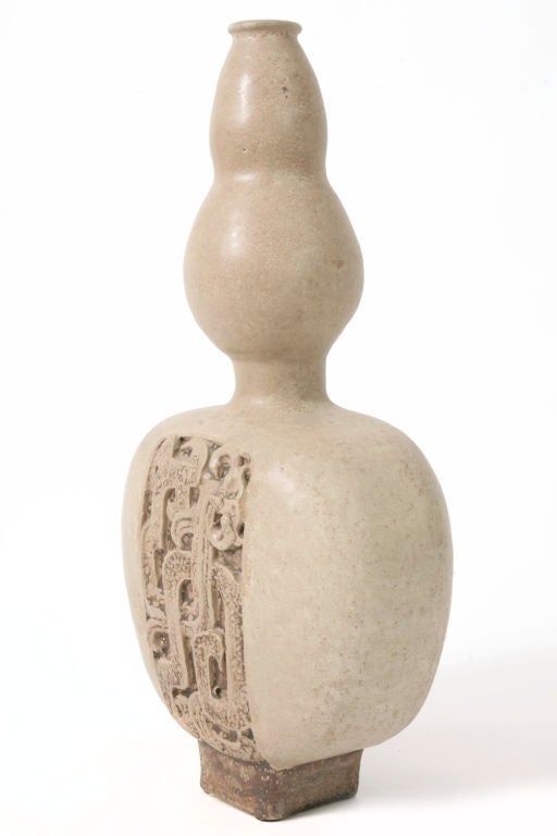 James Fortmann was a potter and professor who taught and produced pottery in California and Arizona. This piece was done in the mid 1950's and is a three tiered bulbous form in a natural stone glaze with a pre Columbian woven motif on the front and