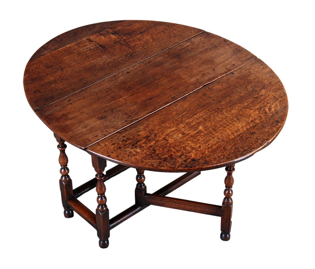 An English oak gate-leg table on turned legs ending in turned toes and connected by square stretchers. With a drawer in one end. The thick top with a figured grain interspersed with medullary rays. Lovely color.