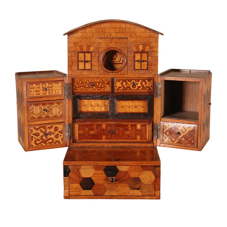 A Japanese box in the form of a house with an arched roof. Marquetry veneered in a number of different woods. The body opens up to reveal a fitted interior above a lower drawer.