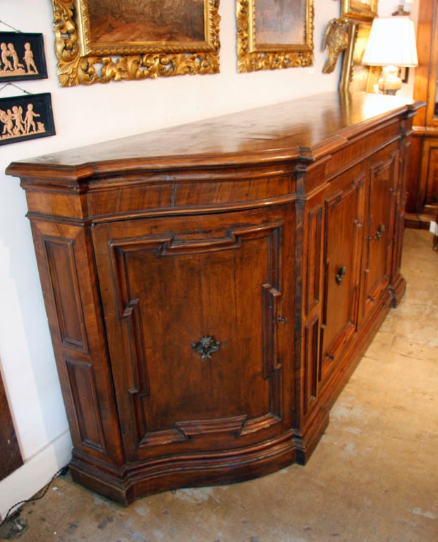 Large, four-door, Tuscan, hand-carved walnut buffet with serpentine sides, bracket front doors, and bronze handles. The whole featuring raised panels and lion's head embellishments. 