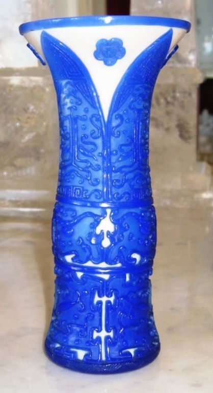 Exquisitely carved Chinese Peking glass blue and white vase. It is a form of cameo glass with white as the base layer with an overlay of blue. It has been carved to form a relief of an intricate geometric design. There is a signature at the bottom.
