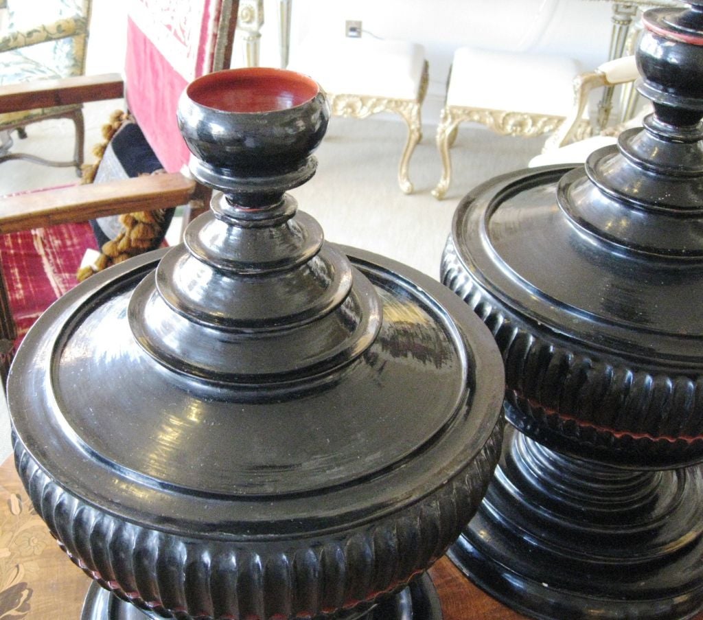 A pair of Burmese 19th century Khantoke or Buddhist offering vessels in black lacquer with red lacquer interiors. The outside edges are fluted in the center with raised ribs from top to bottom. They have several compartments for alms or food