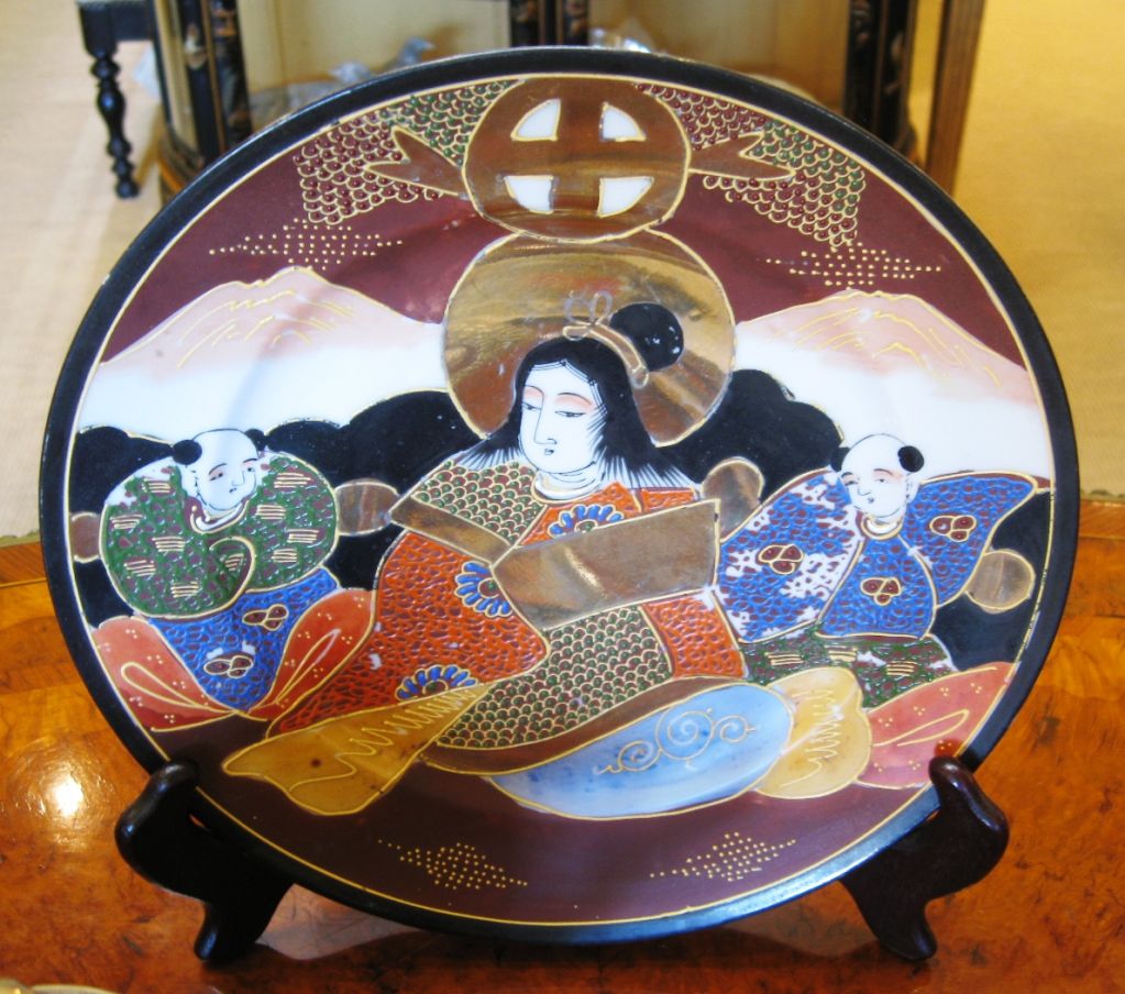 A hand painted Japanese porcelain tea set with six dessert plates, one larger plate, two cups and saucers, creamer, sugar bowl and tea pot. Each plate has a central female figure surrounded by men and each cup reveals a woman's portrait in the