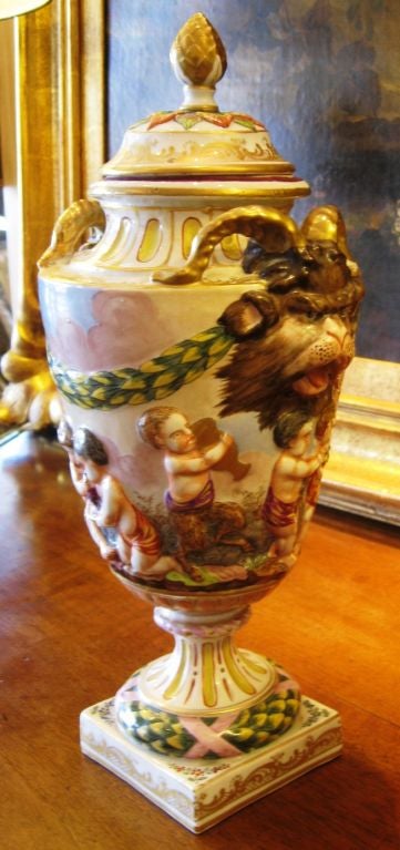 Hand painted 19th century Italian capodimonte lidded urn with cherubs. The overall design depicts cherubs and satyrs gathering grapes and playing. Theyhave garlands in their hair and some are pulling a garland of leaves. There is swagging of laurel