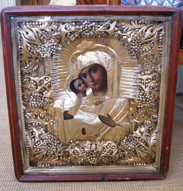 A beutiful Russian icon of the Mother of God of Tenderness. It is elaborately executed in hand cut in gilt and silver foils. The box or 'Kiot' is original to the piece and would have been displayed laying on a table for viewing.