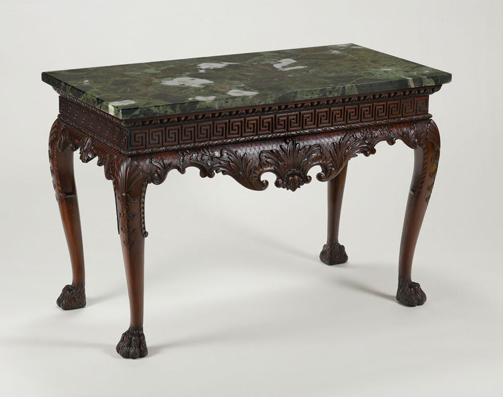 The rectangular verde antico marble top over the egg and dart molded edge and Greek key-carved frieze above the boldly shaped apron carved with scrolling foliage and C-scrolls on a trelliswork ground; raised on cabriole legs carved with shells and