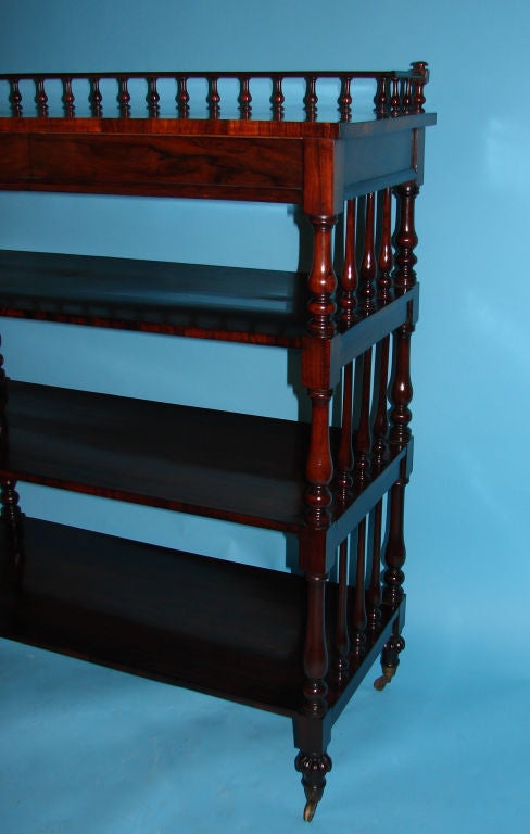An unusual William IV period rosewood etagere, the galleried top over 2 concealed drawers, above 3 shelves connected by turned standards ending in toupie feet on casters. Circa 1835.