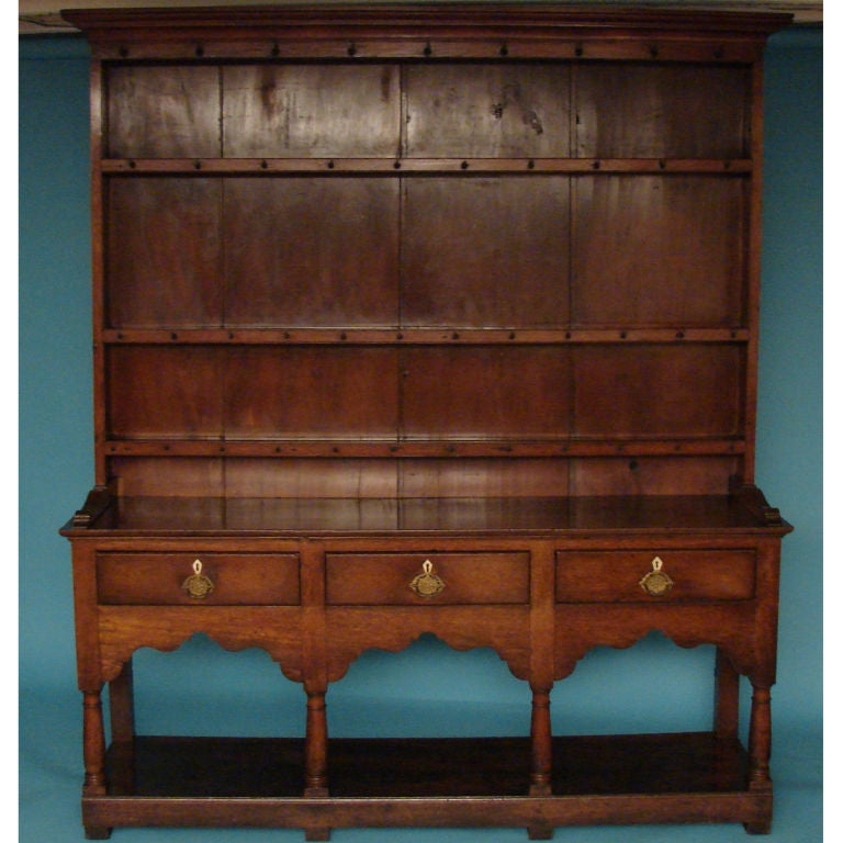 An English oak George III high dresser with 3 shelves over 3 drawers with ivory escutcheons above turned legs terminating in a pot shelf over block feet. Circa 1800.