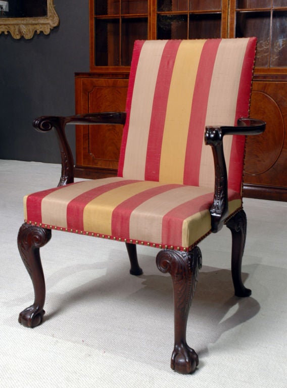 A George II mahogany open armchair with upholstered seat and back having outward scrolled terminating in scrolls supported by a c-scroll carved with acanthus leaves, having acanthus carved cabriole legs, the front legs terminating in ball and claw