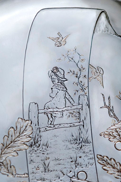 A fine, circa 1880 sterling silver platter- dish by Gorham, of providence, RI, the entire surface chased and engraved with young girl with a hat sitting on a fence, the scene as if on a piece of ribbon, also with birds, branches, berries, grass,