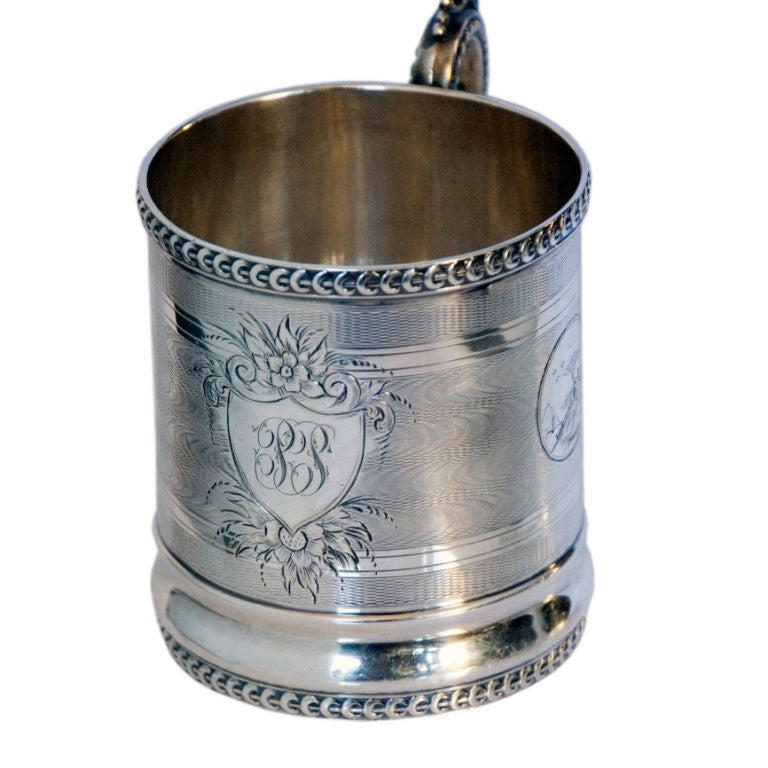A fine circa 1855 coin silver child's cup by R & W Wilson, of Philadelphia, the enitre surface engine turned in a silk moire effect, with two (2) cartouches with rococo revival scentes, the centeral foliate and floral cartouche with monogram, the