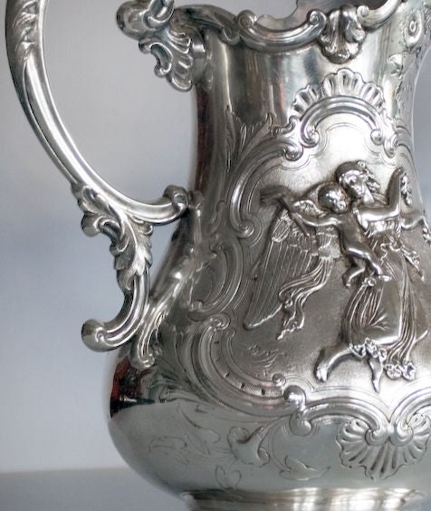 Fine silverplate, chased by hand water pitcher by Hatting Meyer & Warne of Philadelphia, the body with winged female angels, children, birds, foliate and floral designs, with elaborate 's' motif handle.  The chasing on this piece is superb!   No