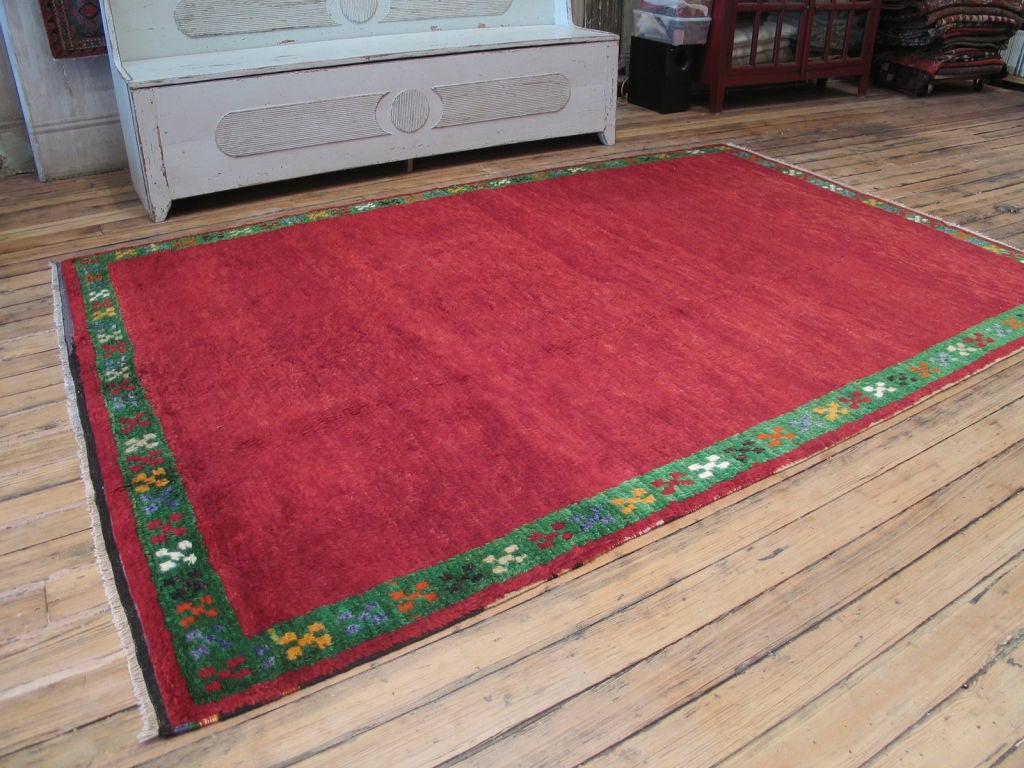 Red Tulu rug with green border. Rug is woven in the 