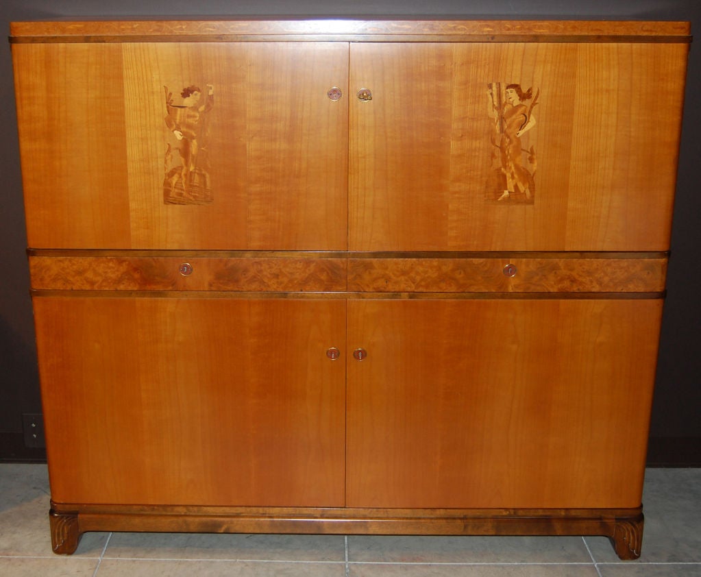 Swedish Art Deco, verging on Art Moderne, storage, bar cabinet in elm, Carpathian Burl elm and dark flame birch with intarsia doors, curved sides and red Bakelite escutcheons. Upper storage area has adjustable shelving and two interior drawers,