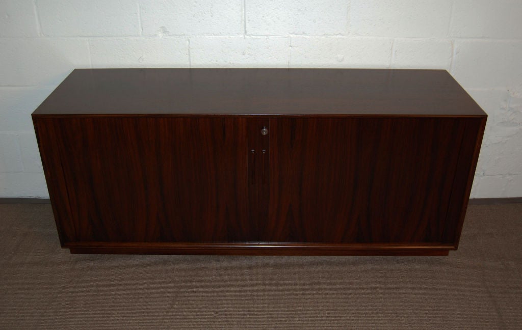 Danish Mid-Century Modern tambour door credenza in jacaranda.  Mahogany interior with four adjustable height drawers.  Key not included - but not needed to operate cabinet doors.

Almost identical to our Ref. No. 1063B.  The veneers are only
