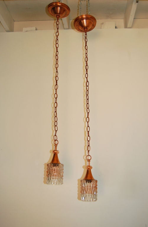 Pair of vintage copper and glass pendant fixtures.  Textured glass body is copper-tinted and clear.  New copper chain and canopies.<br />
<br />
Overall Dimensions of Each Pendant: 4 1/4