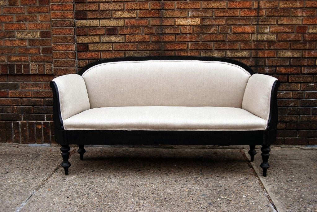 Small American sofa with excellent lines and detail: fine turned legs carved arms and rounded back all in the original black painted finish. The stuffing is firm and it has been recently reupholstered in a glazed linen.