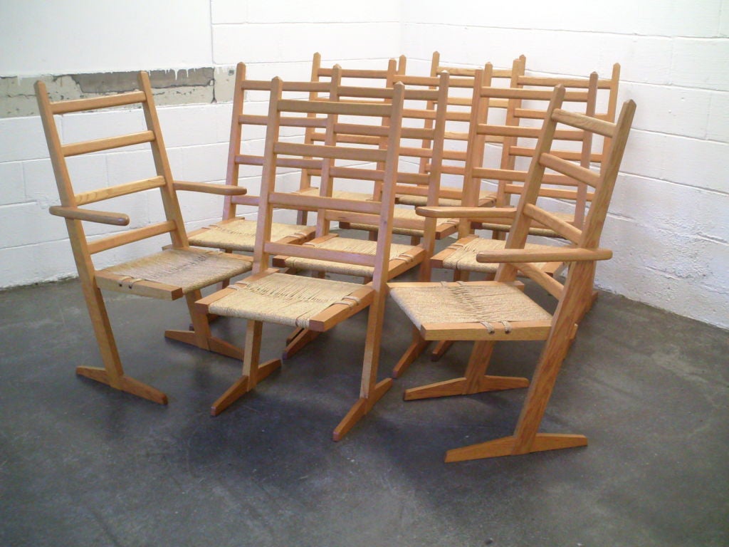 A wonderful Large set of ten Conoid Chairs by Famed Nakashima Staff woodworker Gino Russo.Tall canted Oak rails supporting a large oak seat frame covered in Grass weave caning. Chair resting on the sled foot.Set of ten having eight side and two Arm