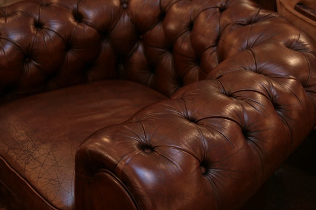 Stunning pair of English Chesterfield club chairs with the original tufted leather upholstery.