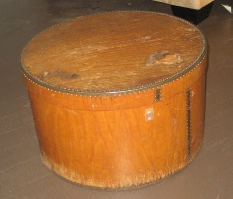 Vintage hat box from France from 1910. Circular hat box is made constructed on wood with a metal detail around edges.