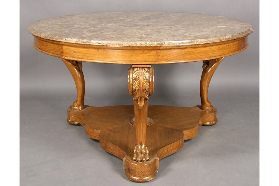 Monumental empire style marble top, gilt accented, center table with carved cabriole legs and paw feet over a shaped platform base.
