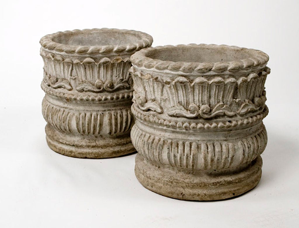 Pair of grey cement cylindrical garden cache pots with rope, bead and acanthus leaf details.