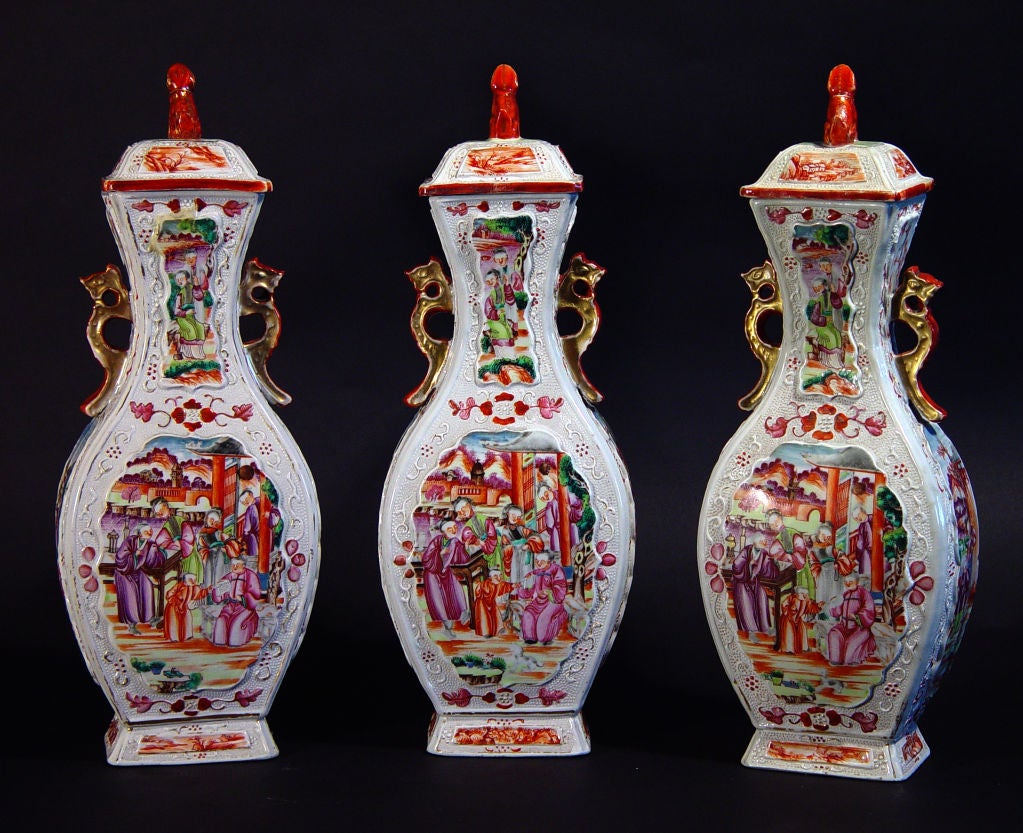 The flattened baluster vases have a chicken-skin ground with shaped panels to front and back enameled in famille rose depicting Chinese Mandarin figures on a balcony of a house with, in one a landscape scene in the background and in the other