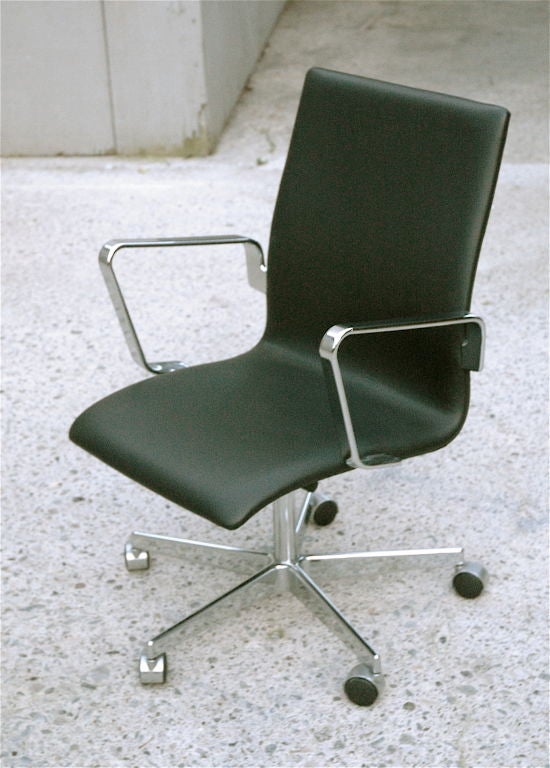 Current Fritz Hansen production example of Arne Jacobsen “Oxford Chair,” Model 3291 desk chair with castors, black leather and aluminum arms. 1965, Denmark.
Originally designed for St. Catherine’s College in 1963. 
Over the years, the chair grew