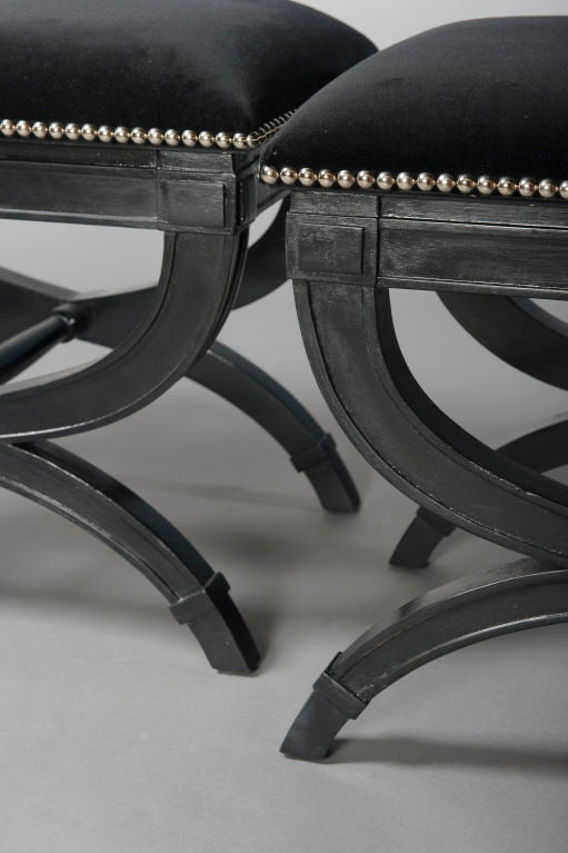 A handsome pair of black painted benches upholstered in black velvet with chrome nail head detail.
