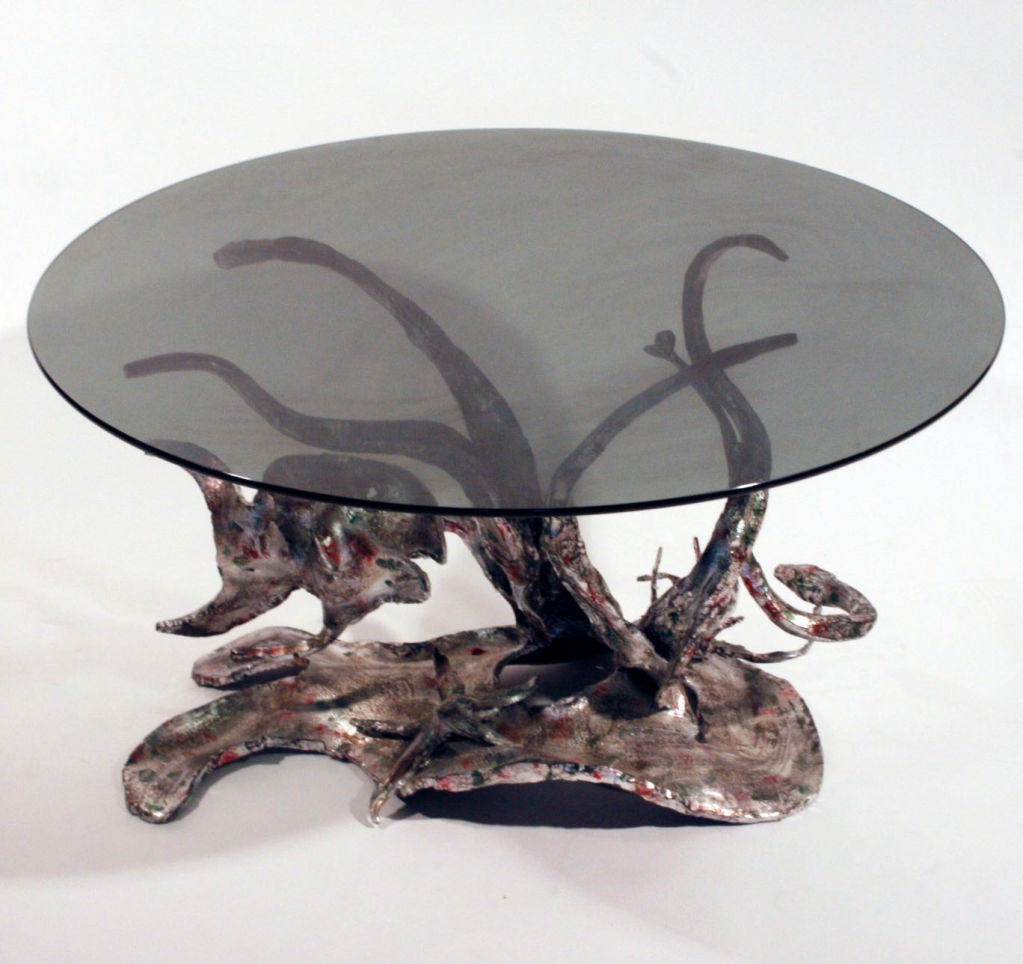 A one off sculptural occasional table depicting marine life.
silver gilt wrought iron with touches of colored enamels, circular smoked glass top.