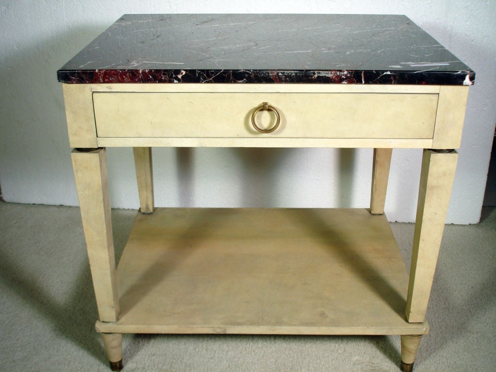 Pair of end tables, circa 1940s, overall parchment veneered, the rouge with white-vein marble over a rectangular frieze fitted with single drawer, supported by four squared tapering legs joint by a rectangular lower tier, standing on circular legs