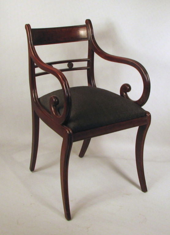 Very fine set of eight classical carved mahogany dining chairs (four shown), having double reeded stiles and legs centering a figured mahogany veneered shaped crest above a horizontal splat with carved rosettes, having slipped out seats with sabre