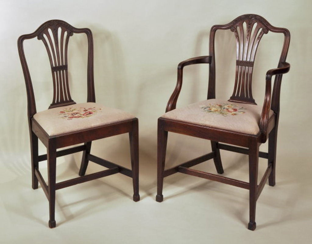 Very fine set of ten George III style carved mahogany dining chairs, comprising eight side and two arm chairs, with molded serpentine crests centering medallion carvings of rice leaves and grains, with vertical pierced splat with husk, leaf and