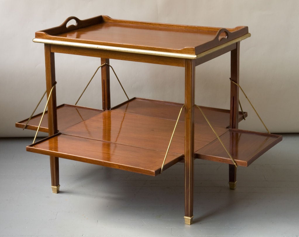 A mahogany Edwardian style tea table with a tray top with brass trim with extending lower leaves<br />
(Width and Depth w. leaves- 30½”  x 39”) Height- 26”