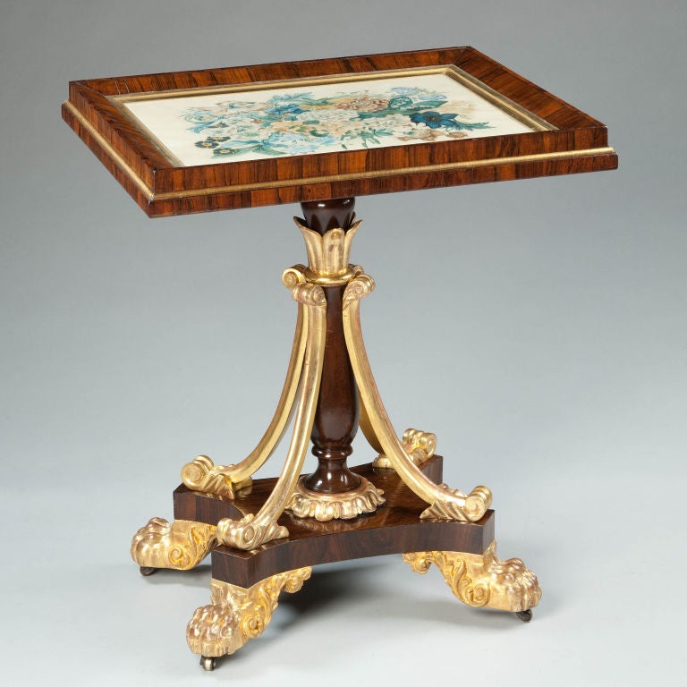 An unusual William IV parcel gilt rosewood occasional table. The square top is fitted with a vellum still life of flowers, in the manner of Redouté. The table stands on a rosewood column surmounted by a gilt capital of laurel leaves and supported by