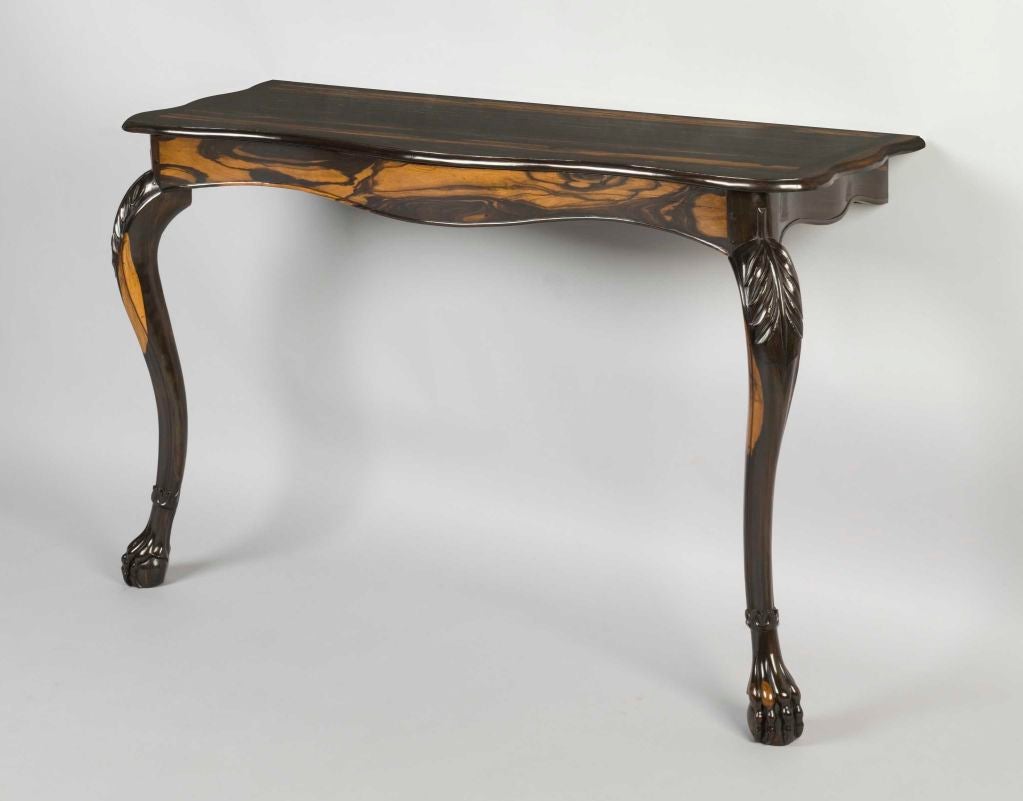A pair of mid 19th century Ceylonese calamander wood console tables, each with a shaped top and moulded edge standing on cabriole legs, the knees enriched with carved foliate ornament and terminating in claw and ball feet.