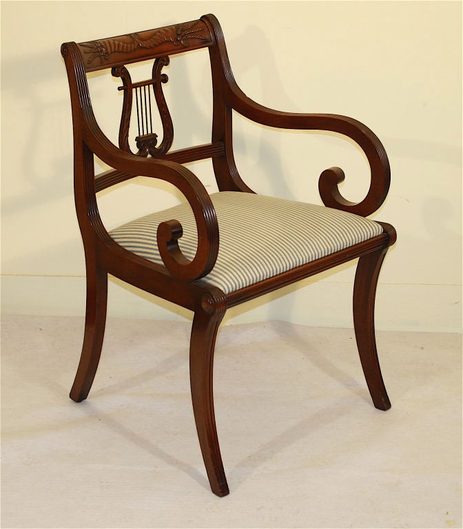 A set of six, 2 armchairs and 4 sidechairs, of klismos form in the manner of Duncan Phyfe.  Reeded mahogany frames and foliate carved crest rails and lyres; brass strung.  The slip seats are freshly upholstered in ticking.<br />
Many 'long' sets of