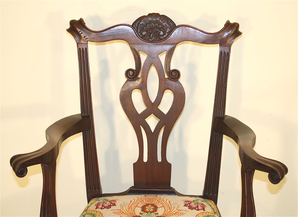 In the Chippendale manner, a single hand-carved mahogany armchair; serpentine crest rail ending in knuckle ears centered with a cabochon cartouche, over a pierced vasiform splat,  fluted stiles, a carved inverted shell on apron front, cabriole legs