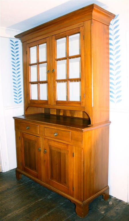 Of Chautauqua County (NY) origin, a two-part 'stepback' cupboard of cherry and pine, with two glazed upper doors enclosing three shelves (two notched for utensil display), and two drawers and two doors in the lower case. The upper case interior is