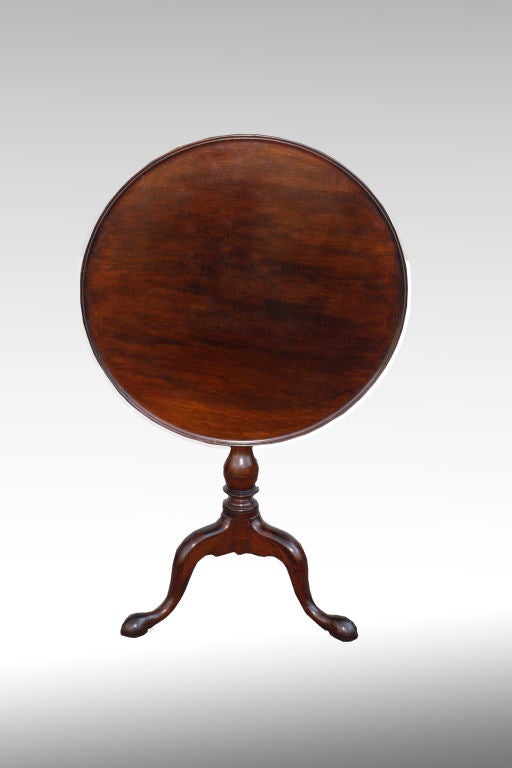 An original finish dark mahogany tilt-top candle stand, on 'bird cage' to permit swiveling. Single board dish rim top. Tripod Queen Anne snake feet. Lancaster or York County, Pennsylvania origin. By the same maker as the slightly smaller candle